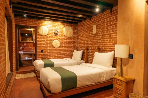 巴克塔普尔Manju Baha Hotel & Restaurant的砖墙客房的两张床