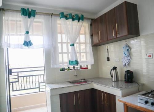 内罗毕bluesky的厨房配有棕色橱柜和带窗帘的窗户。