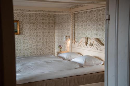 哈姆堡Broløkke Herregård的卧室配有白色的床和床头板
