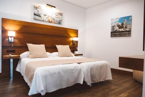 科尼尔-德拉弗龙特拉Ferreira Hostal Boutique的一间卧室配有一张大床和木制床头板