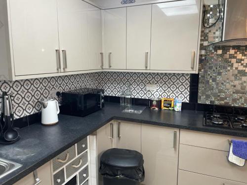 伦敦Rahal Compton的厨房配有白色橱柜和黑色台面