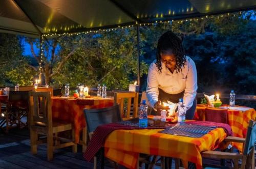 SekenaniDan Maasai Mara safari camp的坐在桌子上的带蜡烛的女人