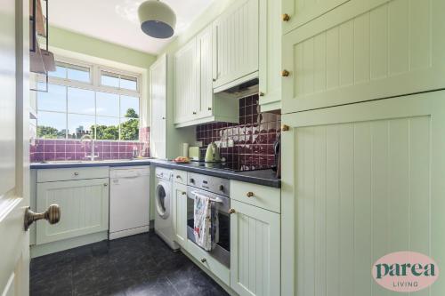 伦敦Parea Living - Stylish Islington 1-Bed Flat, 6min Walk to Tube的厨房配有白色橱柜、洗衣机和烘干机