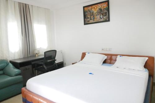 KaraMeka Hotel的卧室配有白色的床、书桌和椅子