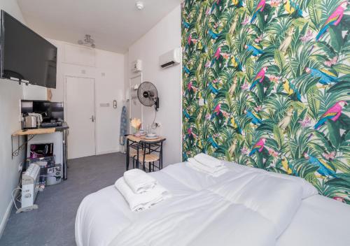 伦敦Private Studio Unit in Chapel Market London的一间卧室配有一张白色床和热带壁纸