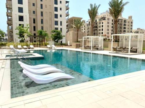 迪拜Dar Vacation - Bright and Charming 1 BR Apartment, Madinat Jumeirah Living的一座带白色椅子的大型游泳池,