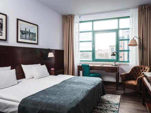 柏林柏林亚美隆亚里安斯普林伯根酒店的配有一张床、一张书桌和一扇窗户的酒店客房