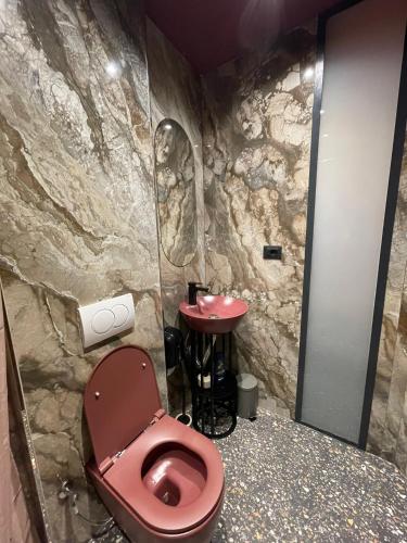 普里兹伦New Soho Hotel的一间带红色卫生间和石墙的浴室