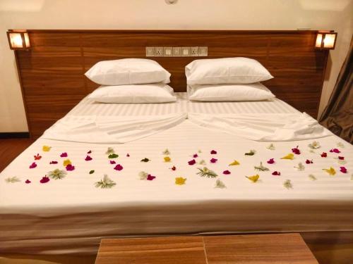 ThinadhooAkiri Grand的一张带鲜花和两个枕头的床
