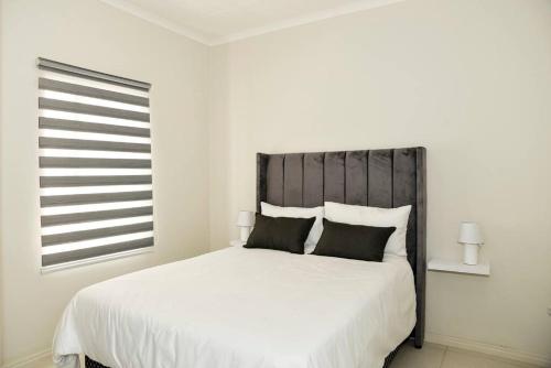 米德兰The Mansioners Apartment的卧室配有一张带黑色枕头的大型白色床。
