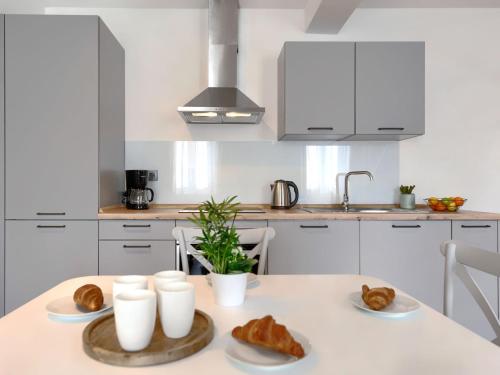 法扎纳Studio Zanet by Interhome的白色的厨房配有带羊角面包和面包的桌子