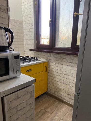 奇姆肯特Апартаменты的厨房配有微波炉和黄色橱柜。