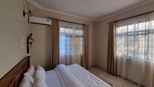 MsarangaMaisha Apartment的一间卧室设有一张床和两个大窗户