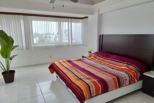 韦拉克鲁斯Departamento con vista al mar y Alberca的一间卧室配有一张带彩色毯子的床