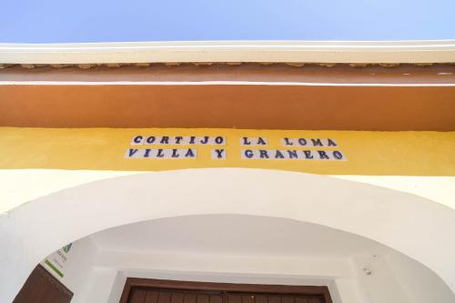 格拉纳达Casa Rural "compartida" La Loma的门廊上标有标志的建筑物入口