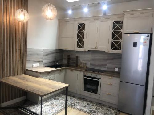 卡拉甘达ЖК Новый Степной的厨房配有白色橱柜、冰箱和桌子
