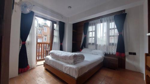 帕坦Bishram Homes的一间卧室设有一张床和两个窗户。