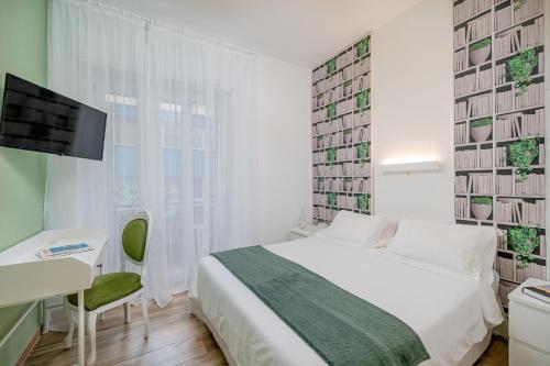 卡利亚里Residenze Asproni Serviced Apartments的一间卧室配有一张床、一张书桌和一台电视