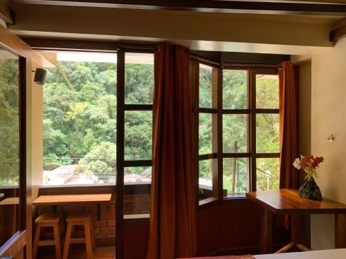 马丘比丘全景住宿加早餐酒店的客房设有大窗户、桌子和椅子。