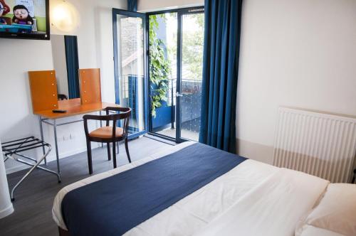 巴黎太阳酒店的一间卧室配有一张床、一张书桌和一个窗户。