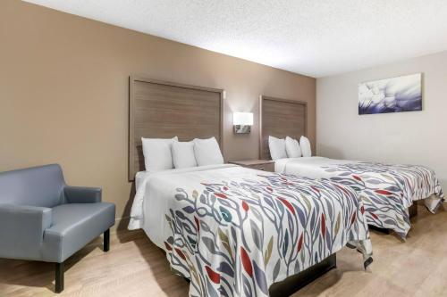 纽波特纽斯Red Roof Inn & Suites Newport News的酒店客房,设有两张床和一张蓝色椅子