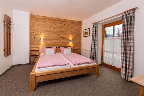 贝希特斯加登Haus Vogl的一间卧室配有一张带粉色床单的床和一扇窗户。