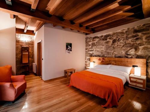 Pazos de Arenteiro阿尔迪帕索斯德阿仁泰洛乡村民宿的一间卧室设有一张床和石墙