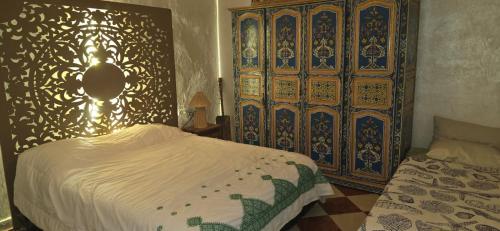 马拉喀什DAR SARSAR airport的一间卧室配有一张床和一个大型木制橱柜
