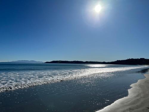 欧尼坦基Whisper Cottage的阳光照耀在水面上的海滩