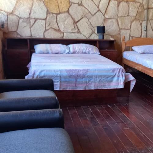圣贝纳迪诺Cabaña Las Palmeras的一间卧室设有两张床和石墙