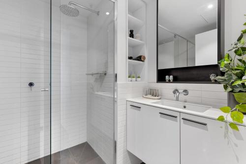 墨尔本Elegant Inner-West 2-Bed with City Views & Pool的带淋浴和盥洗盆的白色浴室