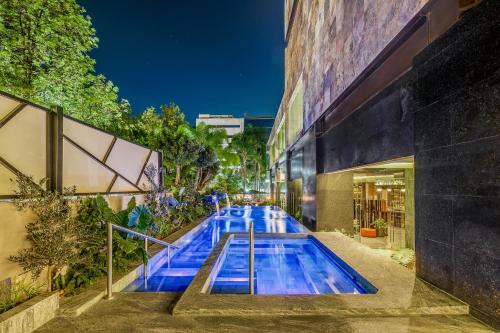 瓜达拉哈拉格兰德瓜达拉哈拉乡村俱乐部费斯塔美国酒店的一座游泳池,在晚上在建筑物前