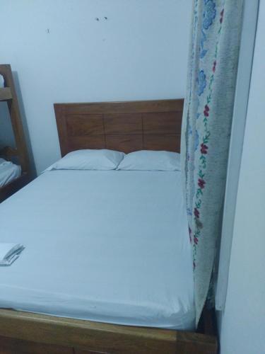 科韦尼亚斯Coveñas Mary plaza的一张带白色床单的床和窗帘