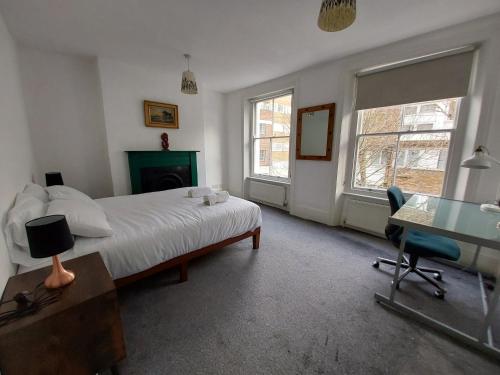 伦敦Large Serene Victorian Abode in Central London的一间卧室配有一张床、一张书桌和一张书桌