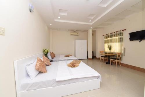 Mỹ AnKhách sạn Đồng Tháp - Hoàng Gia Minh Lợi的一间白色的大房间,配有两张床和一张桌子