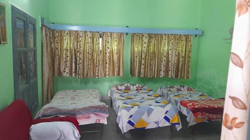 AyodhyaKarunanidhan Homestays的配有两张床铺的绿色墙壁和窗帘