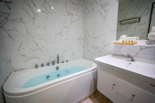 Khao YaiBaan Plaifah Khao Yai Hotel的白色的浴室设有浴缸和水槽。