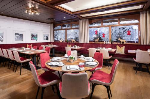 滨湖采尔ALPIN- Das Sporthotel - SKI IN SKI OUT cityXpress, SUMMERCARD INCLUDED的餐厅设有木桌和红色椅子