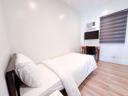 马尼拉SANTOS Pension House的卧室配有白色的床和桌子