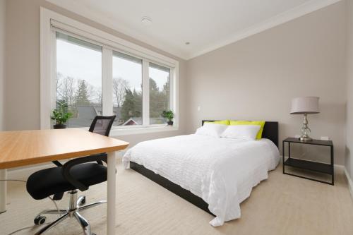 温哥华Dunbar Luxury Homestay的白色卧室设有床、书桌和窗户