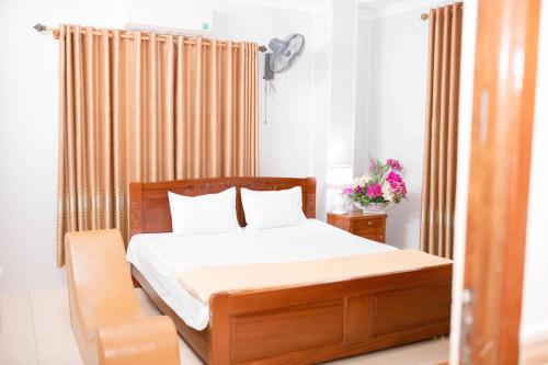 荣市Thảo Nguyên Hotel的一间卧室配有一张带白色床单和枕头的木制床。