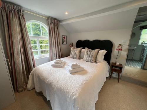 BredonLuxury Cottage with Garden的卧室配有白色的床和2条毛巾