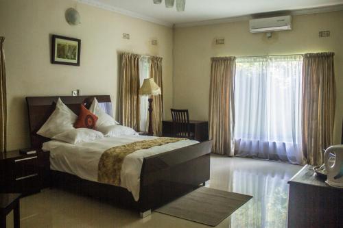 卢萨卡Waterfalls hotel (Lusaka)的一间卧室设有一张床和一个大窗户