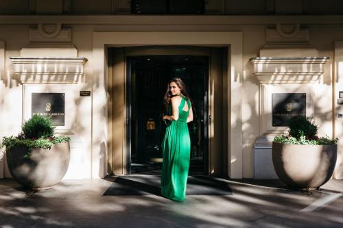 维也纳丽思卡尔顿酒店维也纳酒店的站在建筑物外身穿绿色衣服的女人