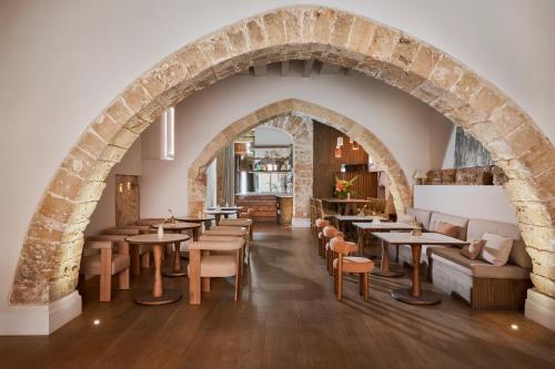 马略卡岛帕尔马波萨达特拉散塔精品酒店的餐厅设有石拱门和桌椅