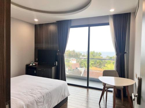 富国Le Anh Hotel的一间卧室配有一张床、一张桌子和一个大窗户