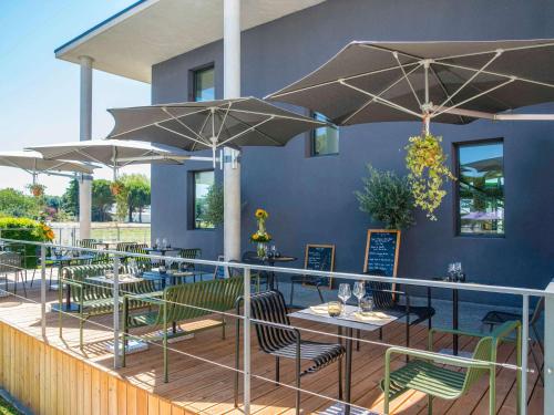 佩尔蒂ibis Styles Pertuis Portes du Luberon的甲板上设有桌子和遮阳伞的餐厅