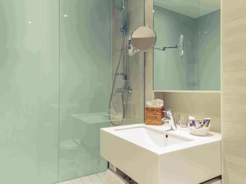 科隆美居科隆贝佛斯特拉瑟酒店的一间带水槽和玻璃淋浴的浴室