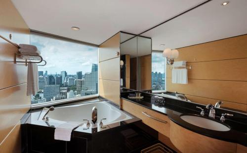 上海上海东锦江希尔顿逸林酒店（入住赠送欢迎曲奇）的带浴缸的浴室和市景窗户。