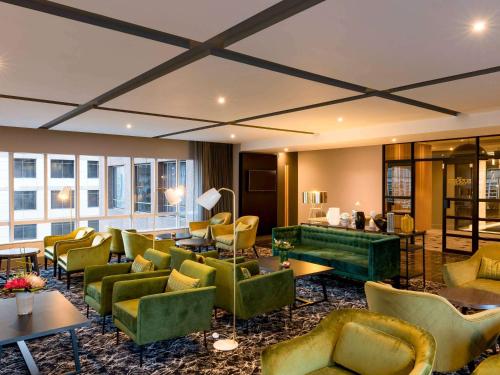 开普敦Pullman Cape Town City Centre的酒店大堂设有绿色的沙发、桌子和窗户。